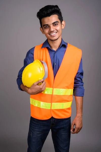 Jovem indiano trabalhador da construção contra fundo cinza — Fotografia de Stock