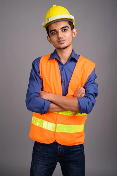 Jovem indiano trabalhador da construção contra fundo cinza — Fotografia de Stock