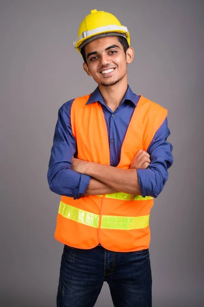 Joven trabajador de construcción indio contra fondo gris — Foto de Stock