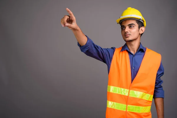 Joven trabajador de construcción indio contra fondo gris —  Fotos de Stock