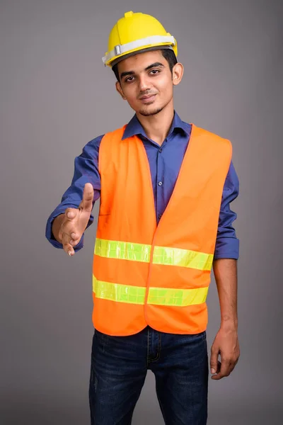 Jovem indiano trabalhador da construção contra fundo cinza — Fotografia de Stock