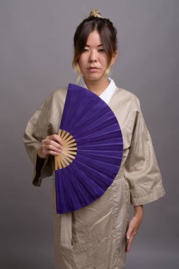 Genç güzel kazak kadın gri bir arka plana dayanır