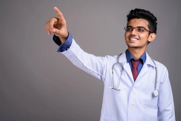 Genç Hintli adam doktor gri bir arka plana dayanır — Stok fotoğraf