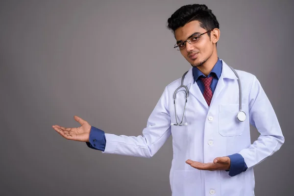 Joven médico indio contra fondo gris —  Fotos de Stock