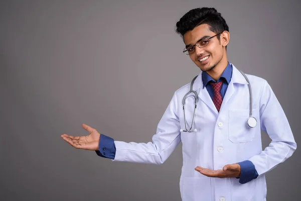 Junger indischer Arzt vor grauem Hintergrund — Stockfoto