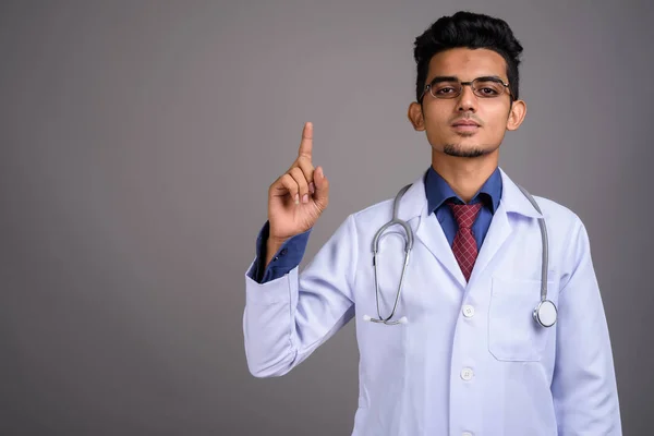 Молодой индийский врач на сером фоне — стоковое фото