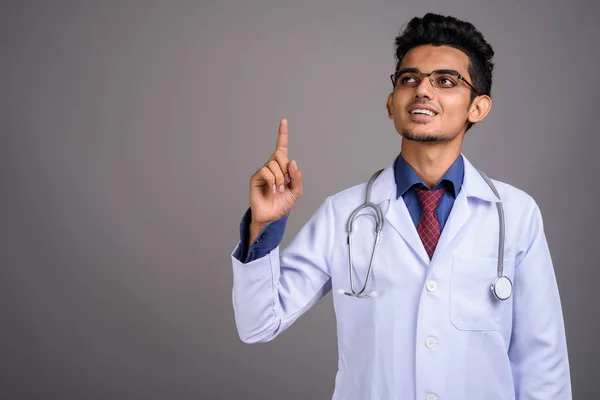 Junger indischer Arzt vor grauem Hintergrund — Stockfoto