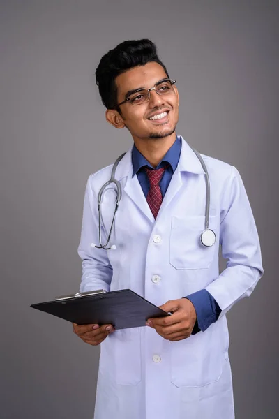 Joven médico indio contra fondo gris —  Fotos de Stock