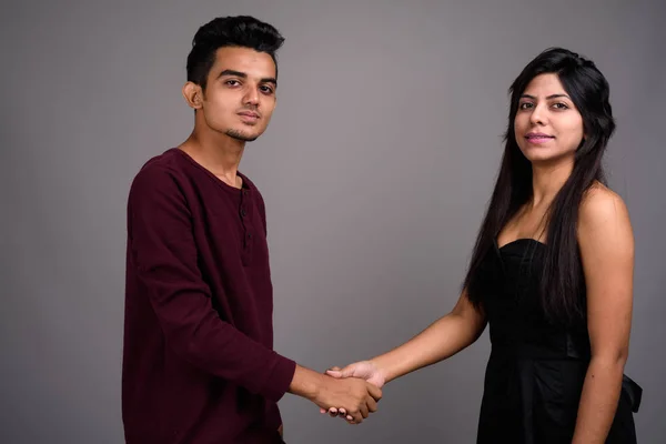 Young Indian man and young Indian woman together against gray ba