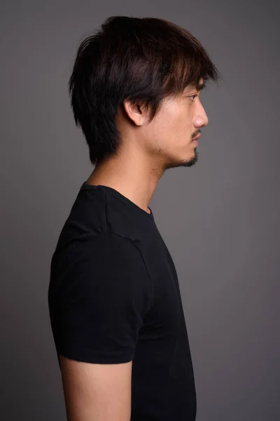 Genç Asyalı adam gri arka plana karşı