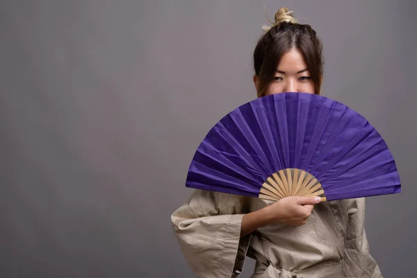 Young beautiful Kazakh woman against gray background