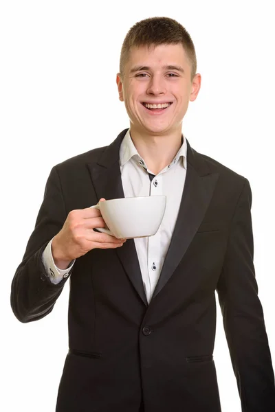 Студийный снимок молодого счастливого бизнесмена, улыбающегося, держа в руках коф — стоковое фото