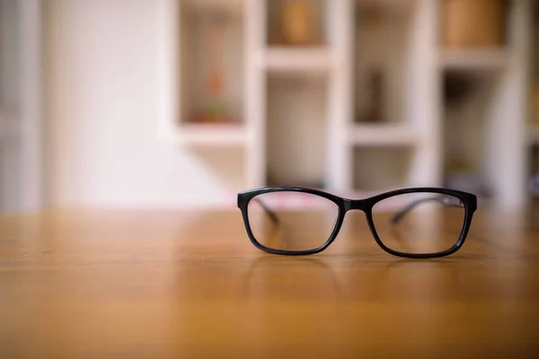 Óculos deitados em cima da mesa de madeira em casa — Fotografia de Stock