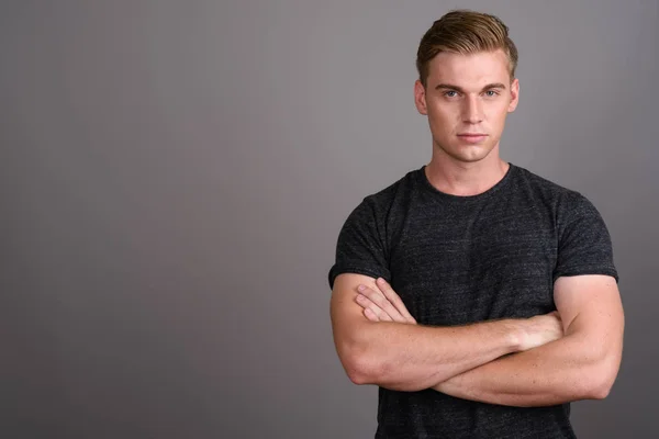 Jovem homem bonito com cabelo loiro vestindo camisa cinza contra gr — Fotografia de Stock