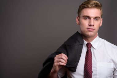 Gri backgrou karşı sarışın saçlı Genç yakışıklı işadamı