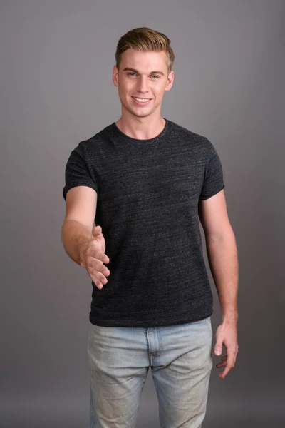 Jovem homem bonito com cabelo loiro vestindo camisa cinza contra gr — Fotografia de Stock