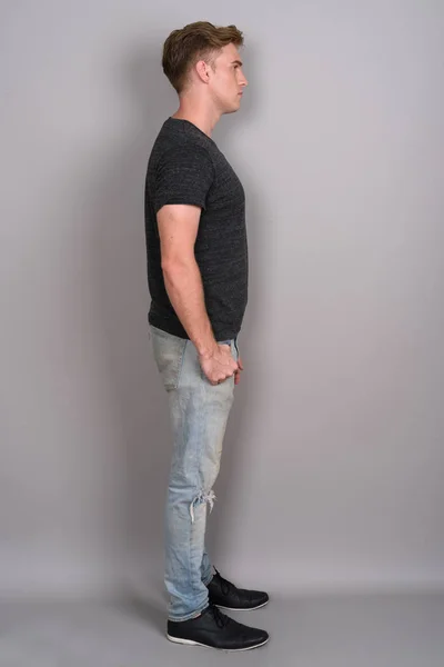 Giovane bell'uomo con i capelli biondi indossa camicia grigia contro gr — Foto Stock