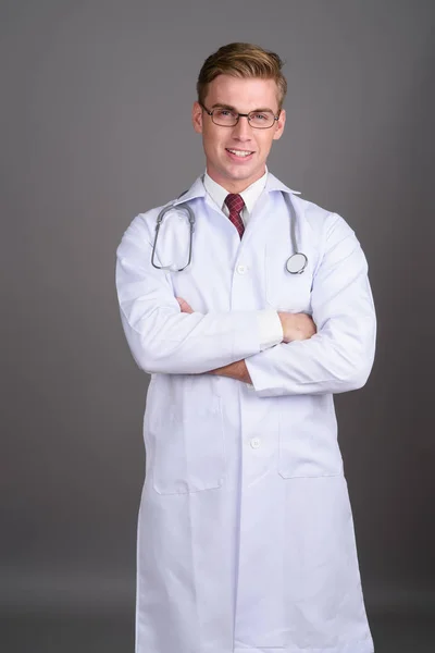 Όμορφος νεαρός γιατρός με ξανθά μαλλιά εναντίον γκρι backgroun — Φωτογραφία Αρχείου