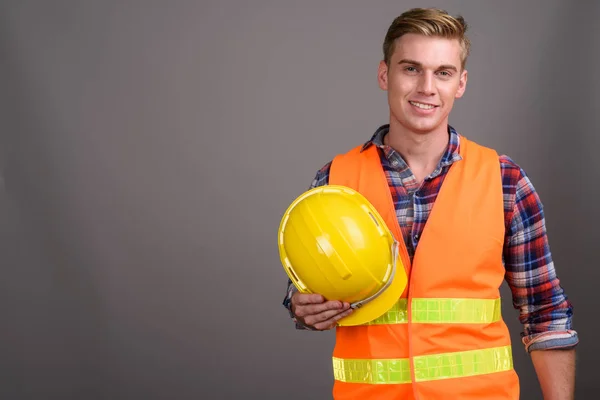 Joven hombre guapo trabajador de la construcción con el pelo rubio contra g — Foto de Stock