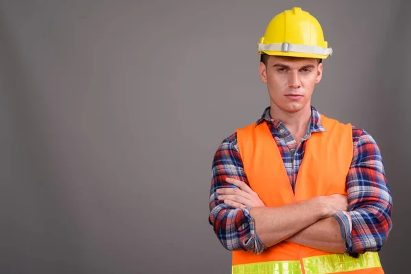 Молодий красивий чоловік будівельник на сірому фоні — стокове фото