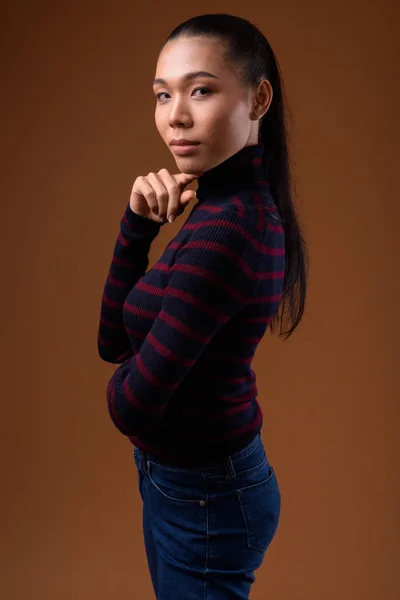 Joven hermosa mujer transgénero asiática contra fondo marrón — Foto de Stock