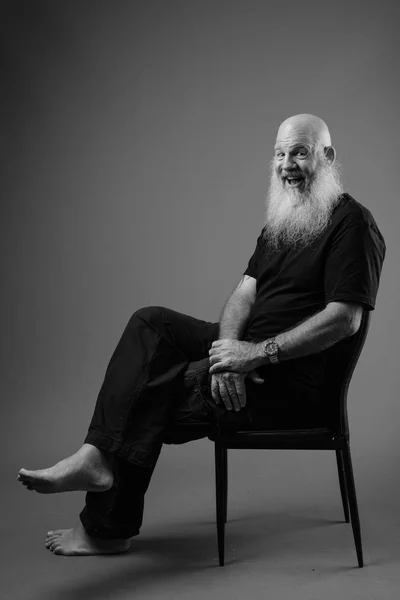 Černobílý portrét starší plešatý muž s plnovousem sezení — Stock fotografie