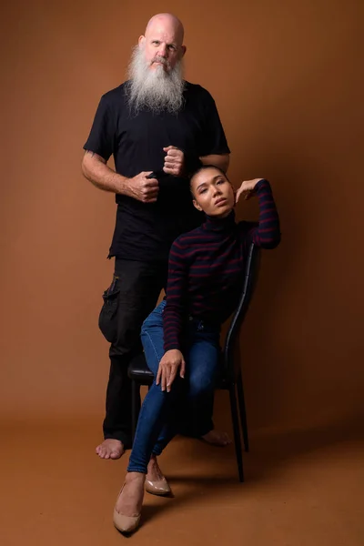 Mature bearded bald man with young Asian transgender woman