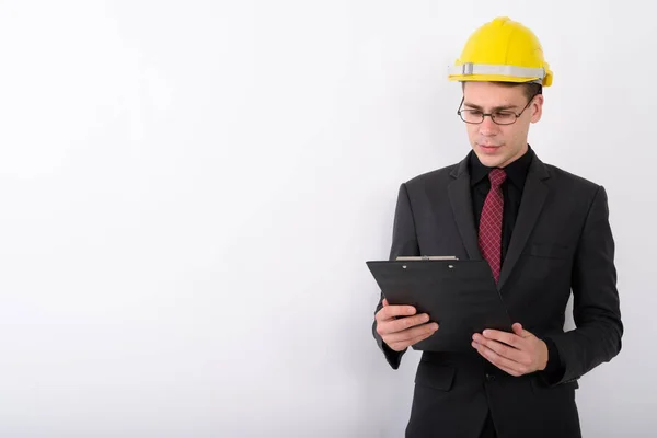 Joven hombre de negocios guapo vistiendo hardhat contra backgro blanco — Foto de Stock