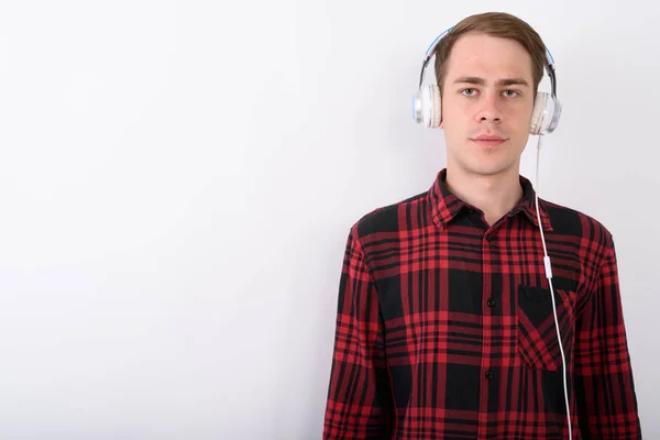 Jovem homem bonito ouvindo música contra fundo branco — Fotografia de Stock