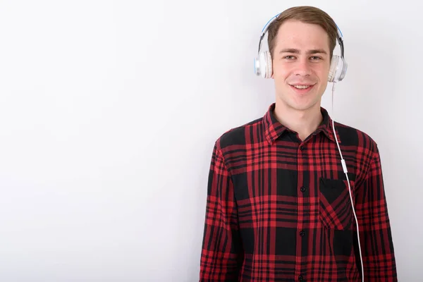 Junger gutaussehender Mann hört Musik vor weißem Hintergrund — Stockfoto