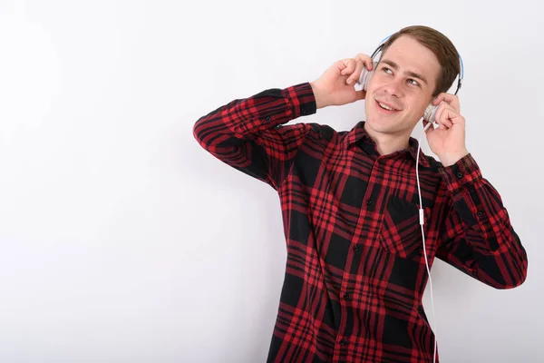 Jovem homem bonito ouvindo música contra fundo branco — Fotografia de Stock