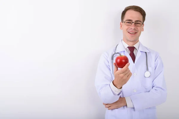 Όμορφος νεαρός γιατρός φοράει γυαλιά εναντίον λευκό backg — Φωτογραφία Αρχείου