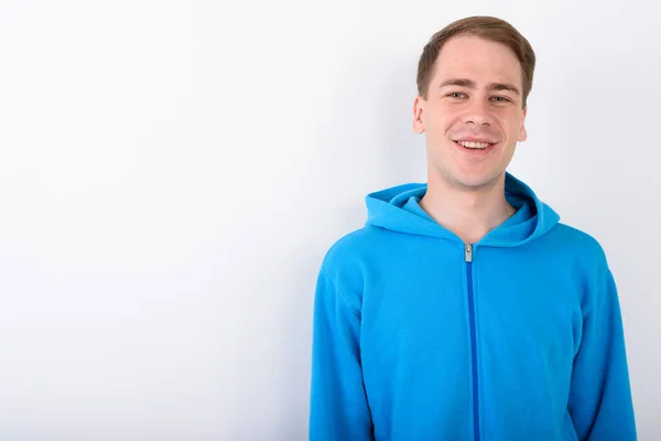 Jonge knappe man dragen blauwe hoodie tegen witte achtergrond — Stockfoto