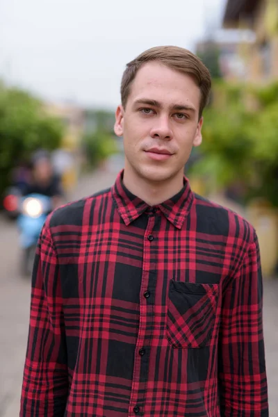 Jeune bel homme portant une chemise à carreaux rouges dans les rues ou — Photo