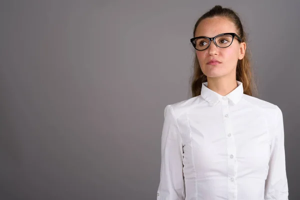 Junge schöne Geschäftsfrau vor grauem Hintergrund — Stockfoto