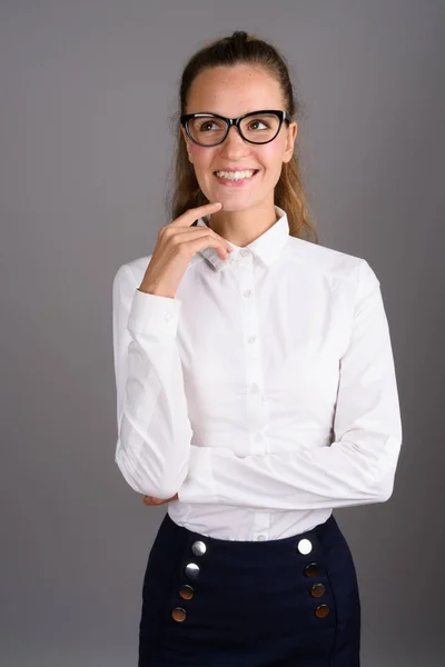 Young beautiful businesswoman against gray background — Stock Photo, Image