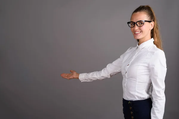 Jonge mooie zakenvrouw tegen de grijze achtergrond — Stockfoto