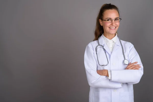 Joven hermosa mujer médico contra fondo gris — Foto de Stock