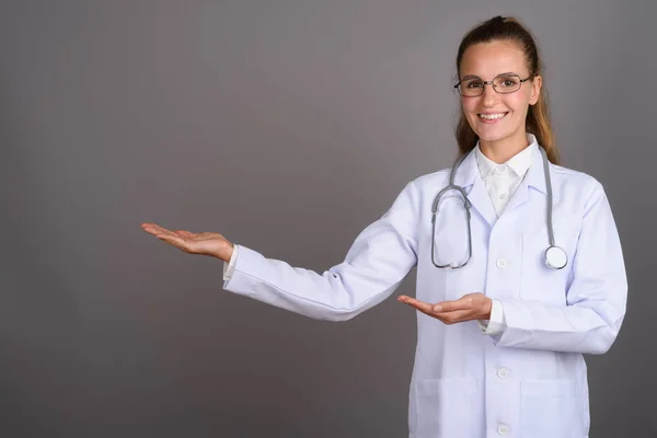 Junge schöne Ärztin vor grauem Hintergrund — Stockfoto