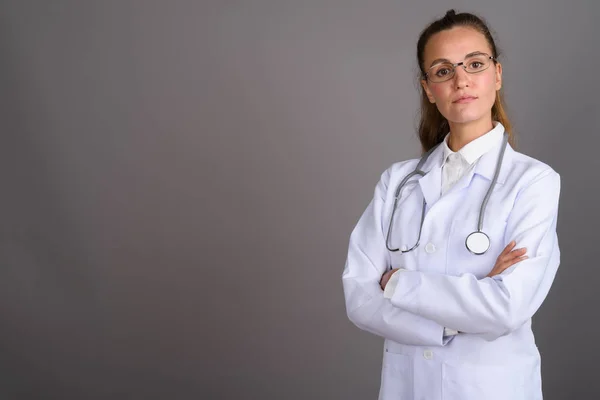 Молода красива жінка-лікар на сірому фоні — стокове фото