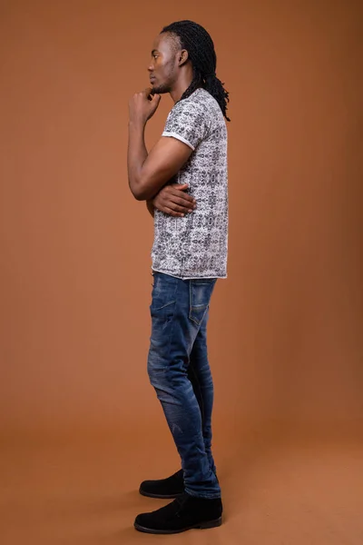 Junger gutaussehender afrikanischer Mann mit braunem Hintergrund — Stockfoto