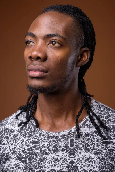 Young handsome African man against brown background — Stock Photo, Image