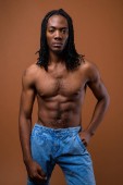 junger gutaussehender afrikanischer Mann ohne Hemd vor braunem Hintergrund