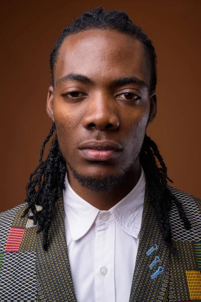 Junger gutaussehender afrikanischer Geschäftsmann mit braunem Hintergrund — Stockfoto