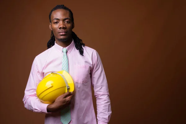 Junger gutaussehender afrikanischer Geschäftsmann mit Bollenhut gegen braune Ba — Stockfoto