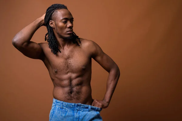 Joven hombre africano guapo sin camisa sobre fondo marrón —  Fotos de Stock