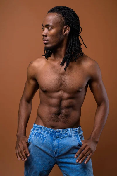 Jeune homme africain beau torse nu sur fond brun — Photo