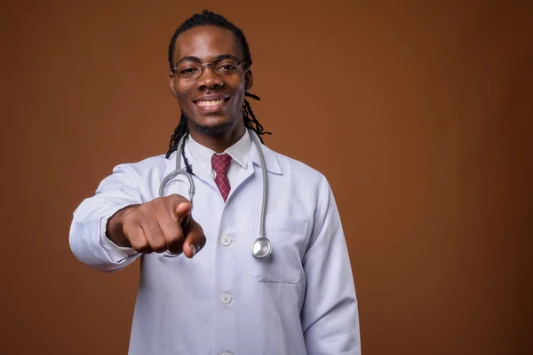 Young handsome African man doctor against brown background — Stock Photo, Image