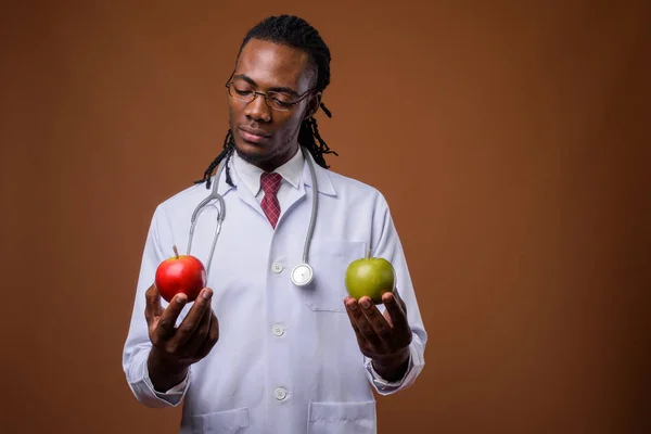 Joven guapo africano hombre médico contra marrón fondo —  Fotos de Stock