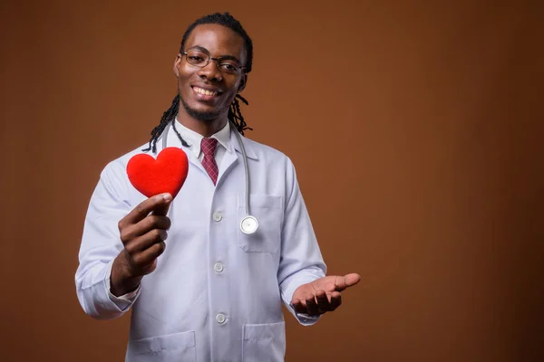 Joven guapo africano hombre médico contra marrón fondo —  Fotos de Stock